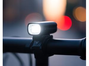 Front view of an urban commuting bike light mounted on handlebars, glowing white.